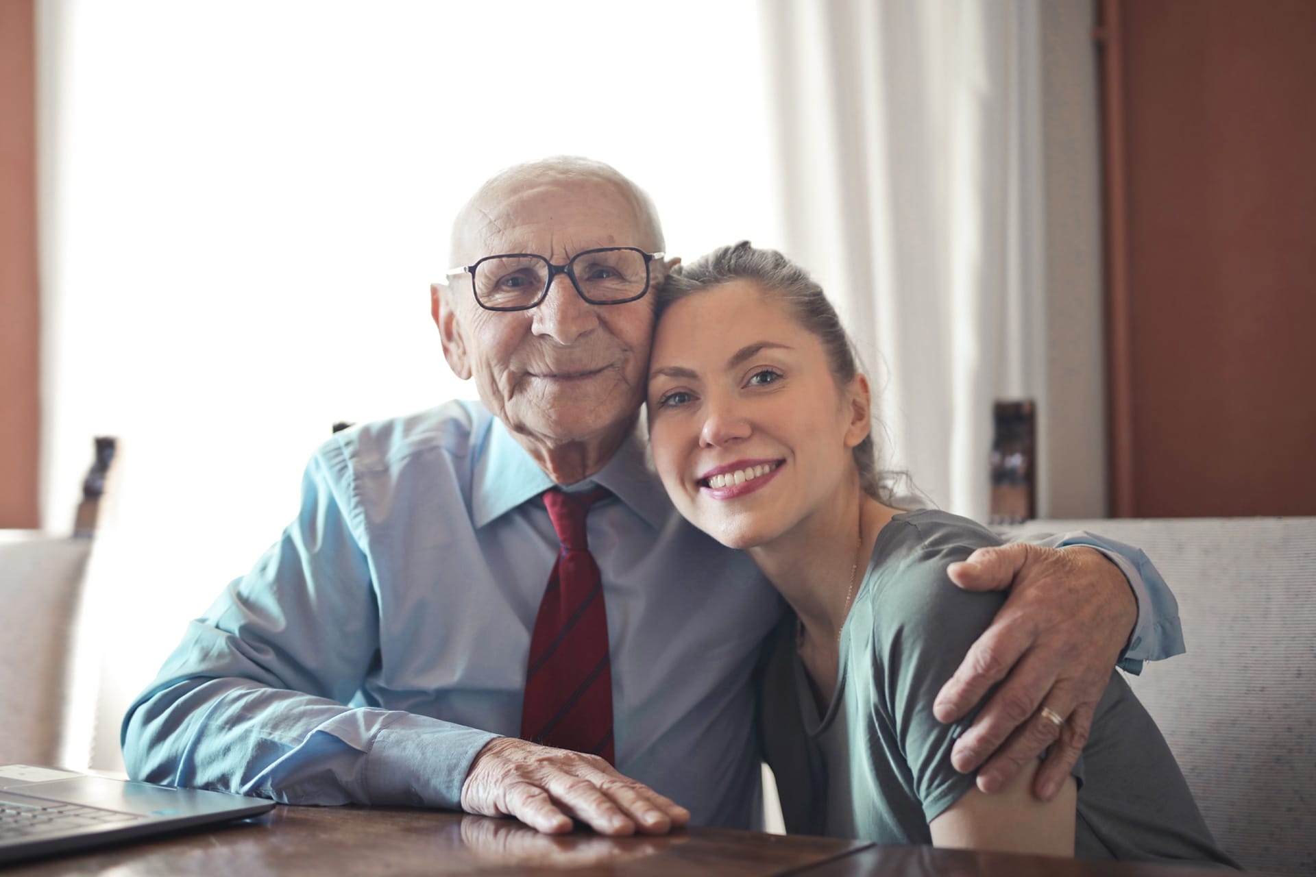 Elderly Man & Caregiver Embraced Facing Camera and Smiling
