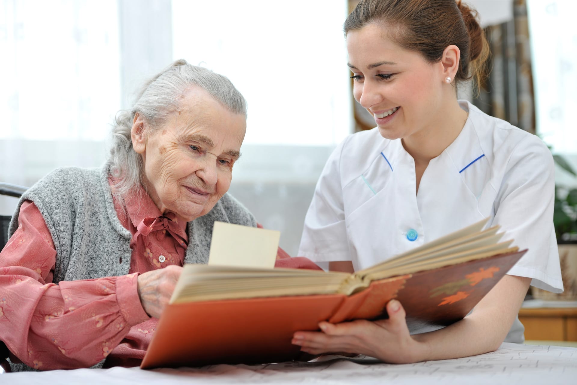 Elderly Woman & Caregiver With Book of Memories